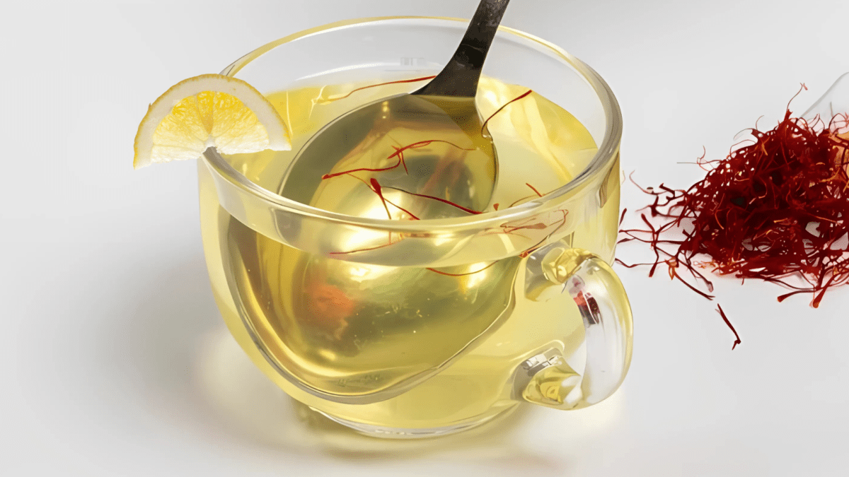 A glass of saffron detox water with vibrant golden color, garnished with lemon slices and mint leaves.