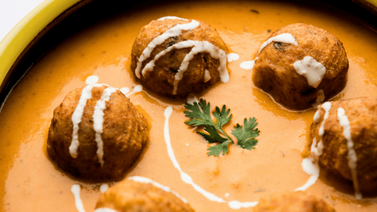 Zafrani Kofta Curry garnished with saffron and nuts in a creamy sauce.